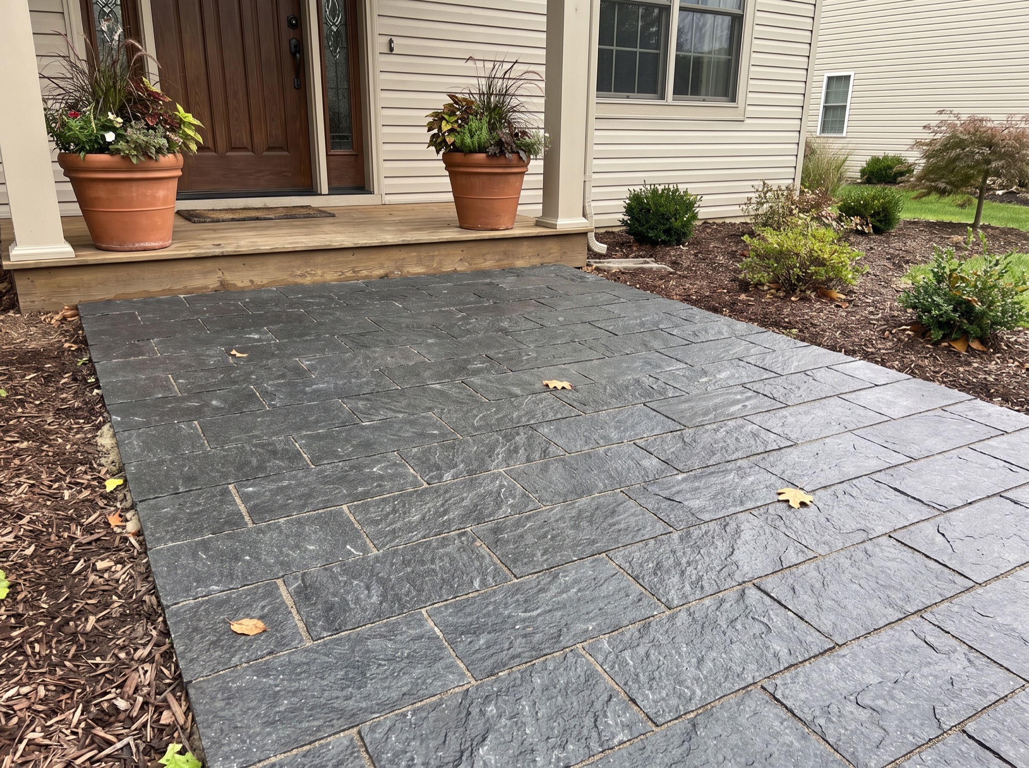 Front entry landing paved with dark splitface granite