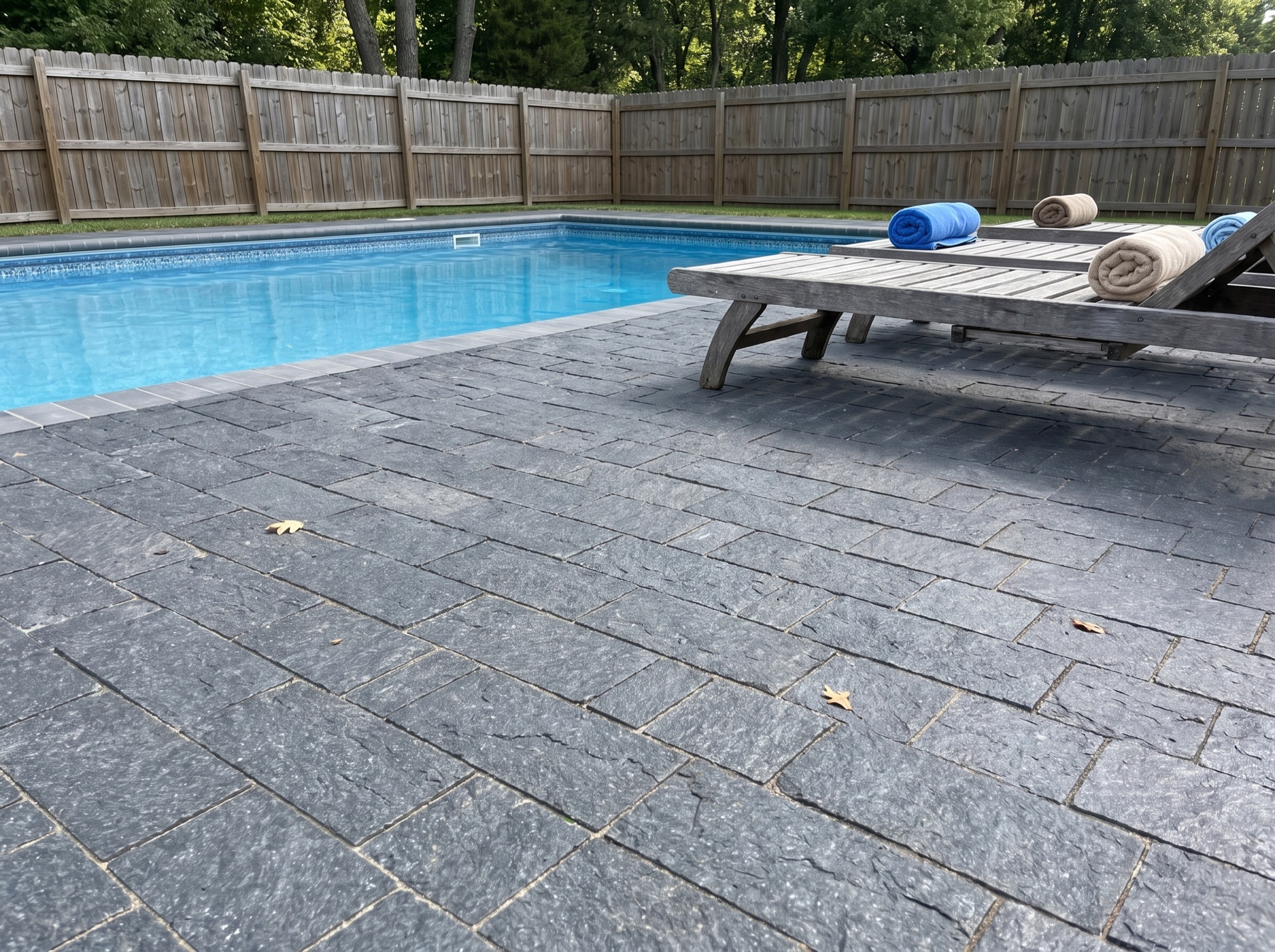 Dark splitface granite pool deck with lounge chairs
