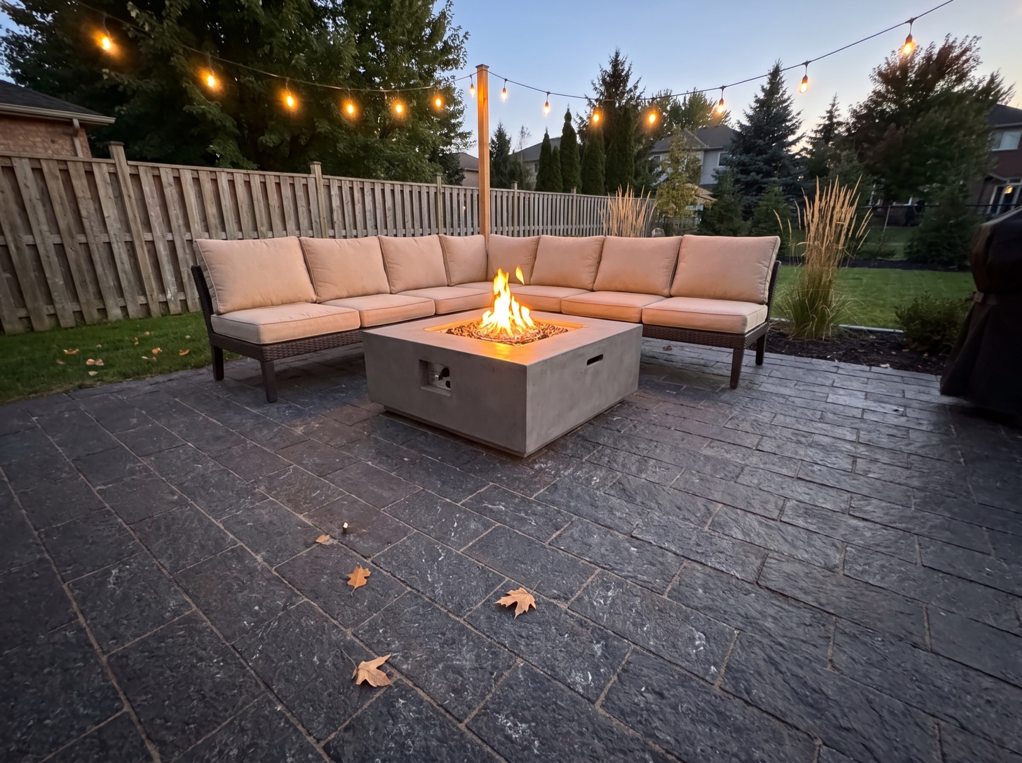 Dark splitface granite patio with a fire table and outdoor sofa at dusk