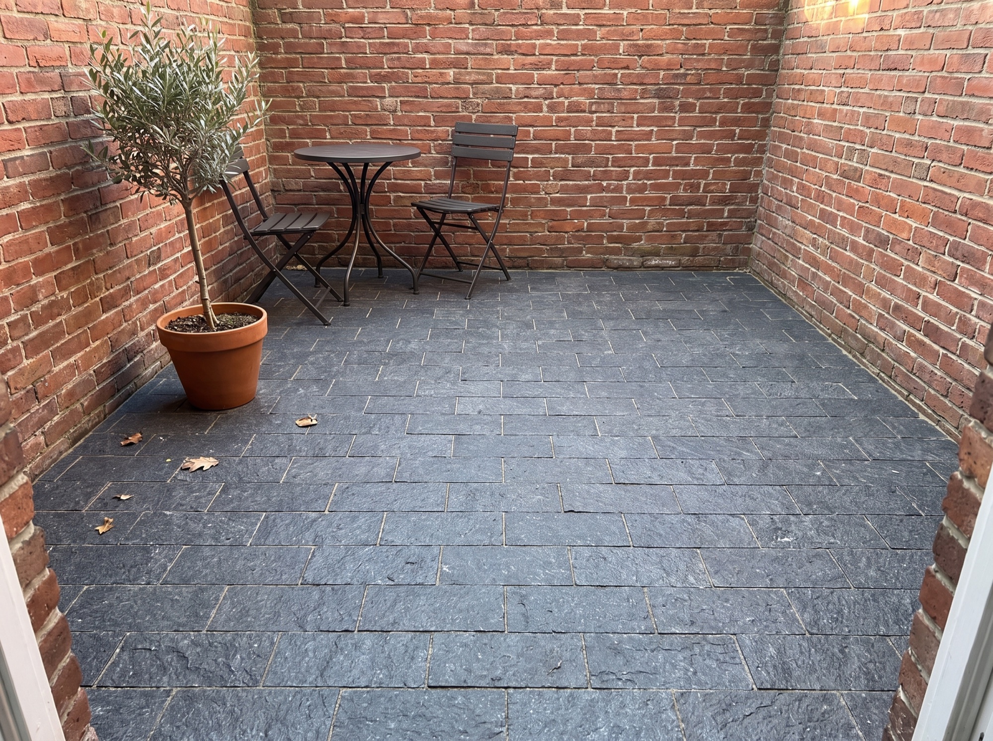 Small brick courtyard paved with dark splitface granite